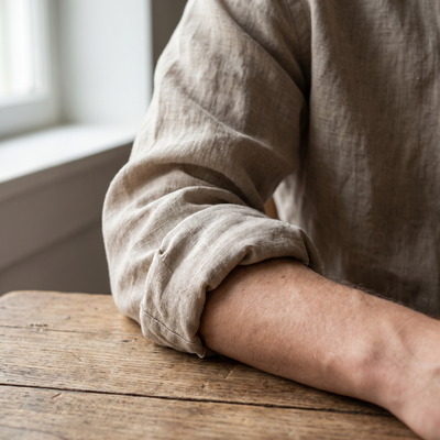 A rolled linen shirt sleeve resting on a wooden table
