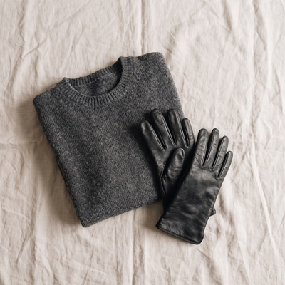A folded knit and leather gloves on pale linen